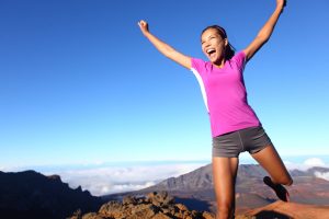 Happy woman doing exercise on a mountaintop