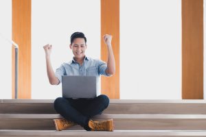 Man with laptop who's excited to finish online courses